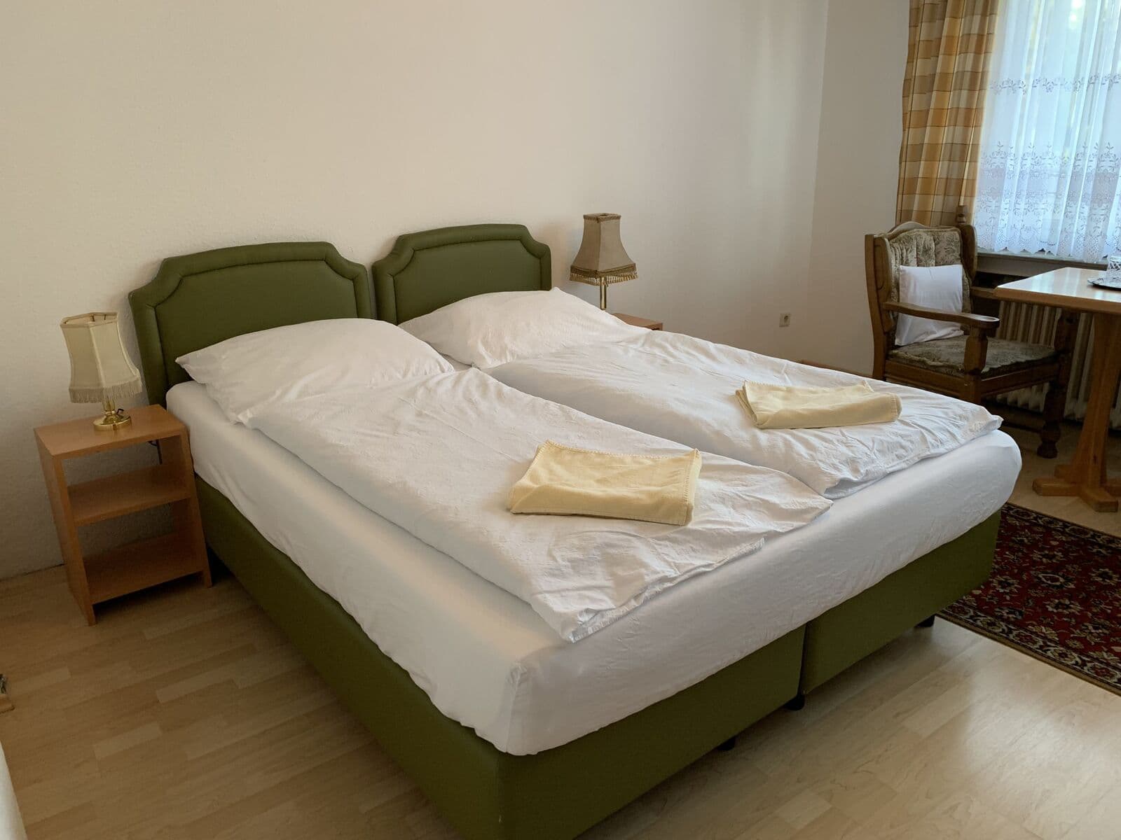 Doppelzimmer im Hotel Jeong in Moers mit Doppelbett, grünem Kopfteil und Sitzecke am Fenster