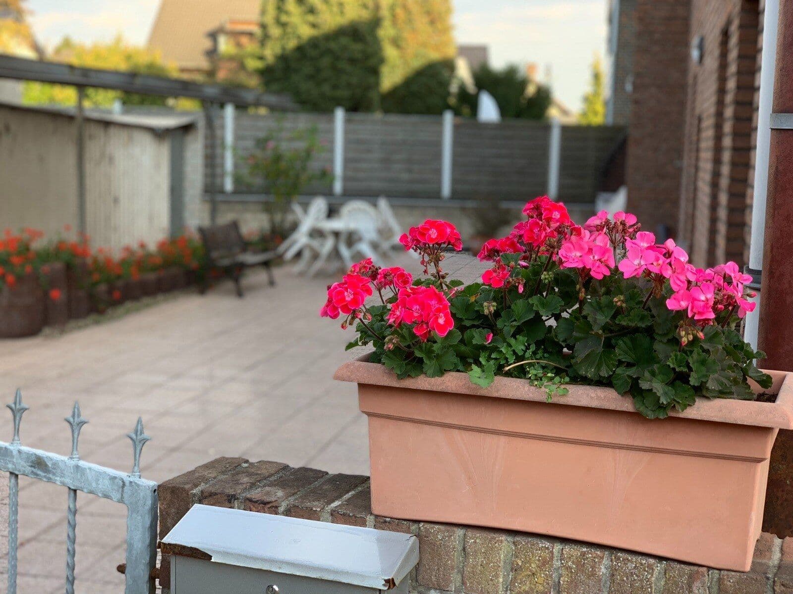 Innenhof des Hotel Jeong in Moers mit pinken Geranien im Blumenkasten und Sitzplätzen